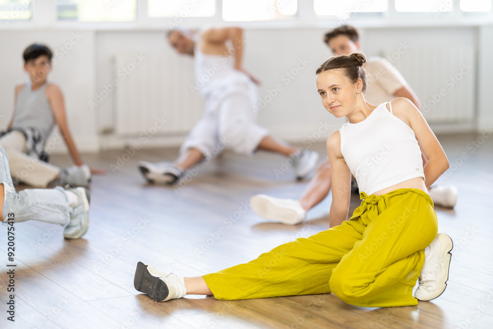 Obraz premium Teenage girl rehearsing breakdance in group in dance studio