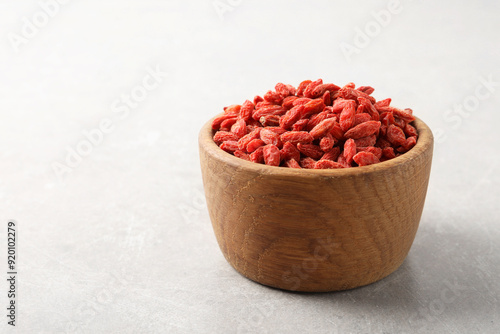 Quadro su tela Dried goji berries in bowl on light grey table, space for text