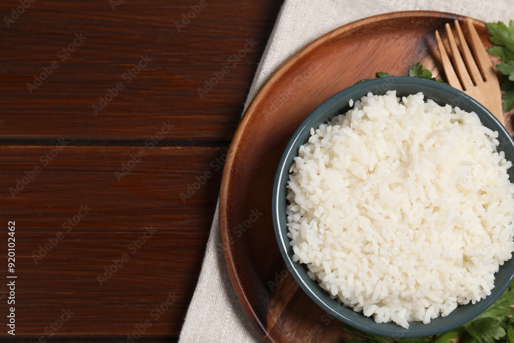 Delicious boiled rice served with parsley on wooden table, top view. Space for text Delicious boiled rice served with parsley on wooden table, top view. Space for text