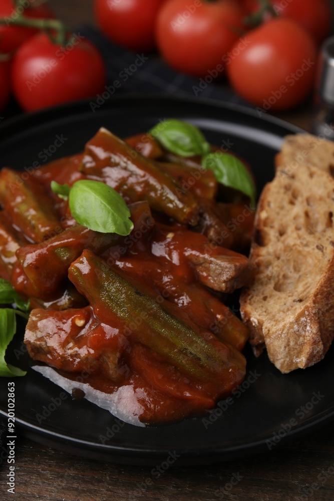 Tasty stew with okra, tomato sauce, bread and basil on wooden table, closeup Tasty stew with okra, tomato sauce, bread and basil on wooden table, closeup