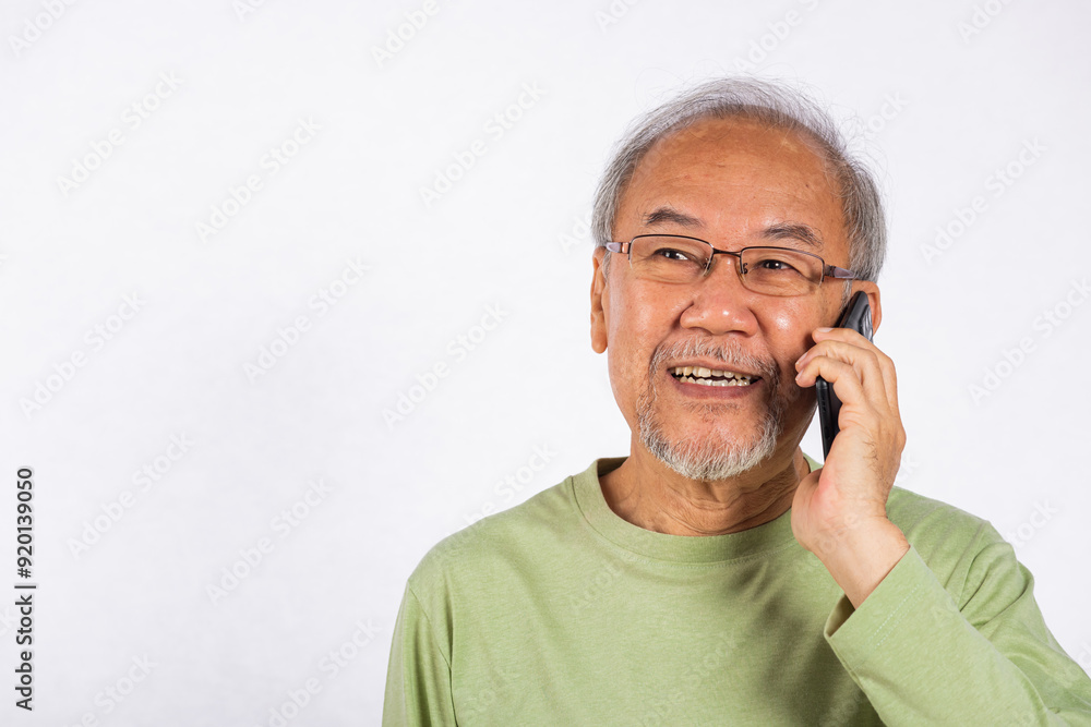 Portrait Asian smiling old man with glasses while talking on his cell phone studio shot isolated on white background, happy senior man calling to someone with mobile phone Portrait Asian smiling old man with glasses while talking on his cell phone studio shot isolated on white background, happy senior man calling to someone with mobile phone