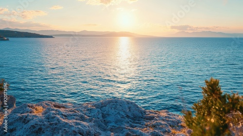 Scenic sunset over tranquil ocean waters, casting golden hues on a rocky shoreline, perfect for nature and travel themes. photo