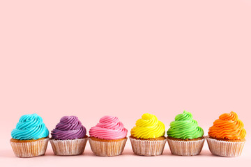 Tasty colorful cupcakes on pink background