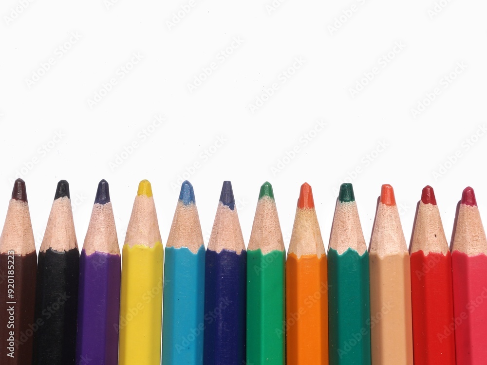 A set of colored pencils drawing pencils are on the background of a white, partially empty room A set of colored pencils drawing pencils are on the background of a white, partially empty room