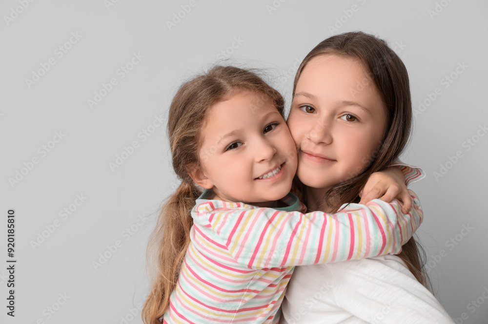 Cute little sisters hugging on light background, closeup Cute little sisters hugging on light background, closeup