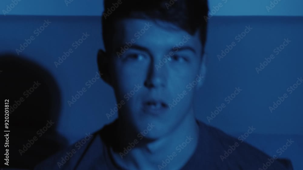 Night terror. Sleep disorder. Disturbed scared guy raised up in bed from nightmare of monster hand shadow on wall late in dark.