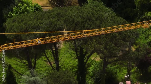 Tower Crane Boom Against Forest Trees At Construction Site In Foce, La Spezia, Italy. drone sideways shot photo