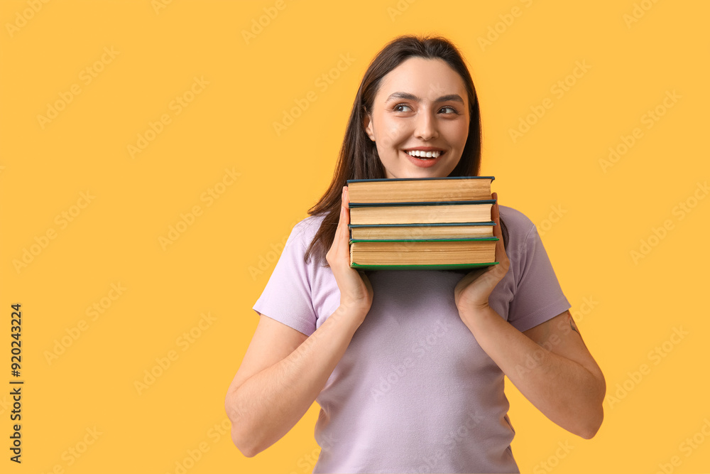 Young happy woman with stack of books on orange background Young happy woman with stack of books on orange background