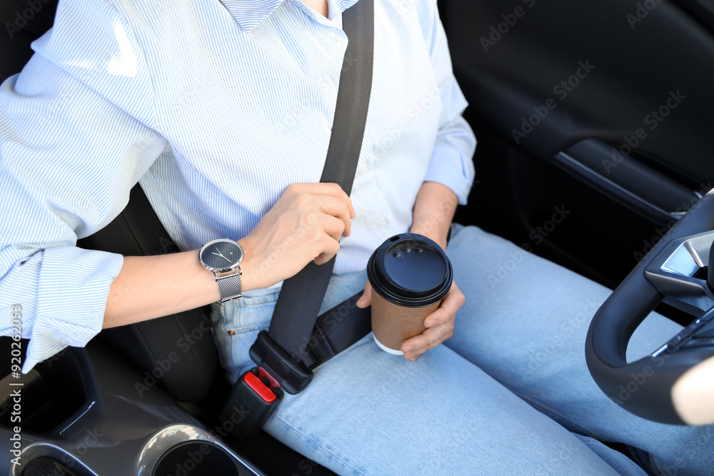 Fastened female driver with coffee cup sitting in car, closeup Fastened female driver with coffee cup sitting in car, closeup