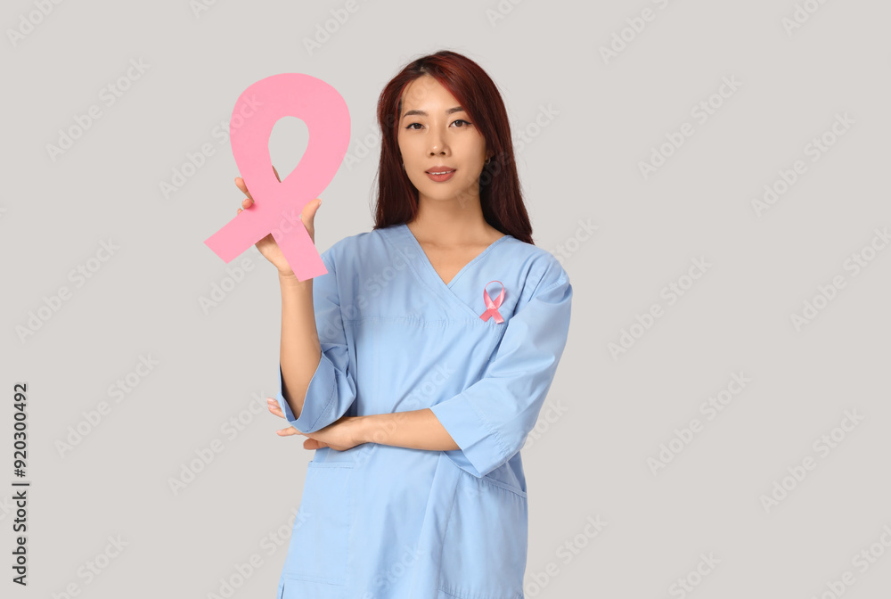 Female Asian doctor with pink ribbon on light background. Breast cancer awareness concept Female Asian doctor with pink ribbon on light background. Breast cancer awareness concept