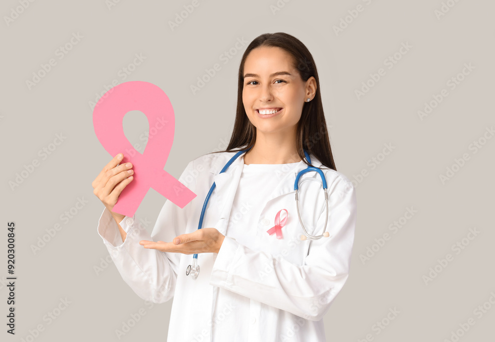Female doctor with pink ribbon on light background. Breast cancer awareness concept Female doctor with pink ribbon on light background. Breast cancer awareness concept