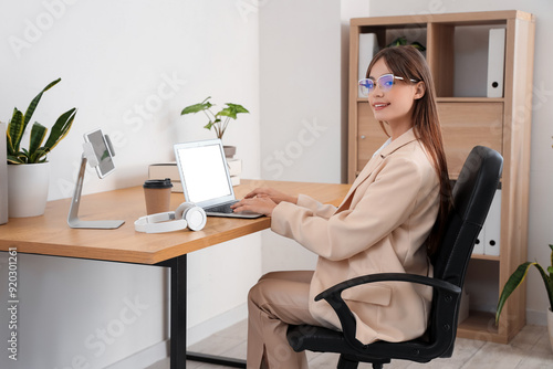 Beautiful young businesswoman working with modern laptop at table in office