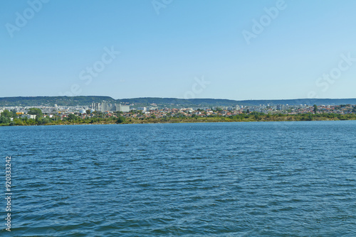 A calm lake with a backdrop of lush green hills and clear blue skies