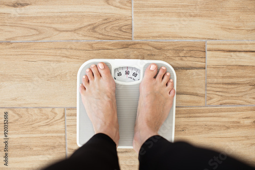 Photos Person standing on scale measuring weight on wooden floor