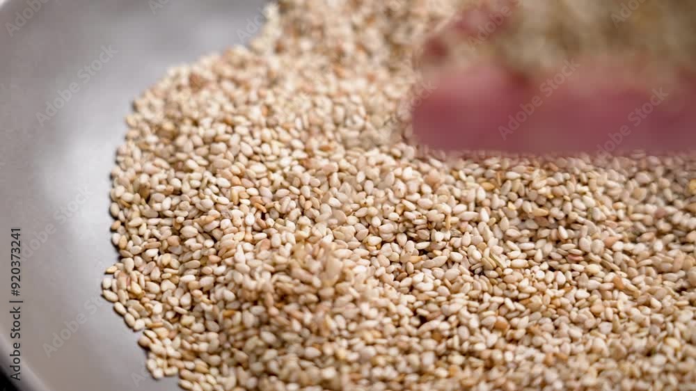 Sprinkling bio seeds from the hand into a gray kitchen plate in slow motion. Natural nutritious flavouring ingredient. Slow motion. Close up Sprinkling bio seeds from the hand into a gray kitchen plate in slow motion. Natural nutritious flavouring ingredient. Slow motion. Close up