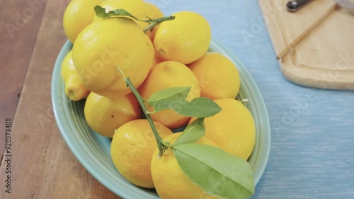 Lemons on a blue oval Fiestaware plate displayed on a wood table photo