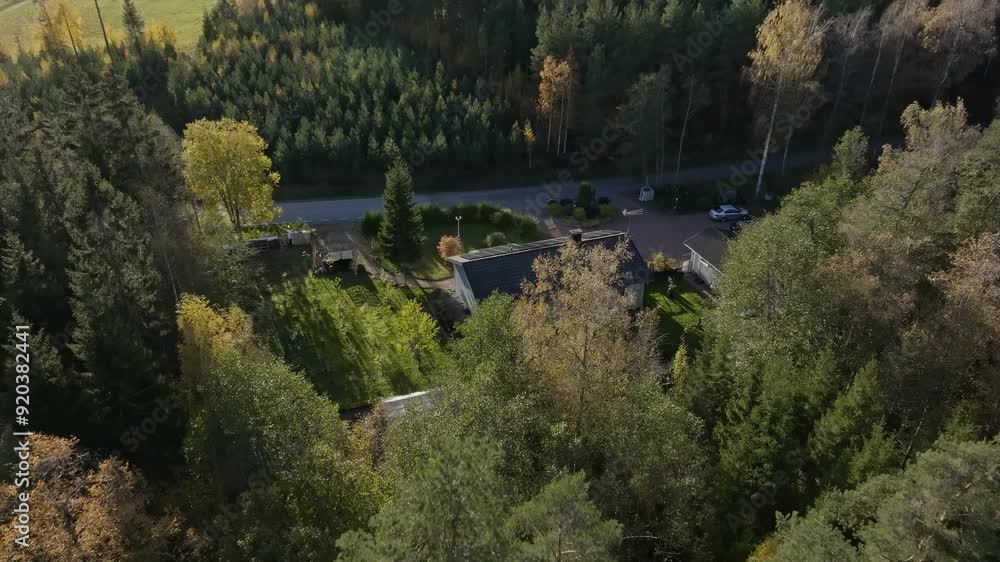 Drone shot over forest, revealing a house with sunlight collectors, autumn day Drone shot over forest, revealing a house with sunlight collectors, autumn day