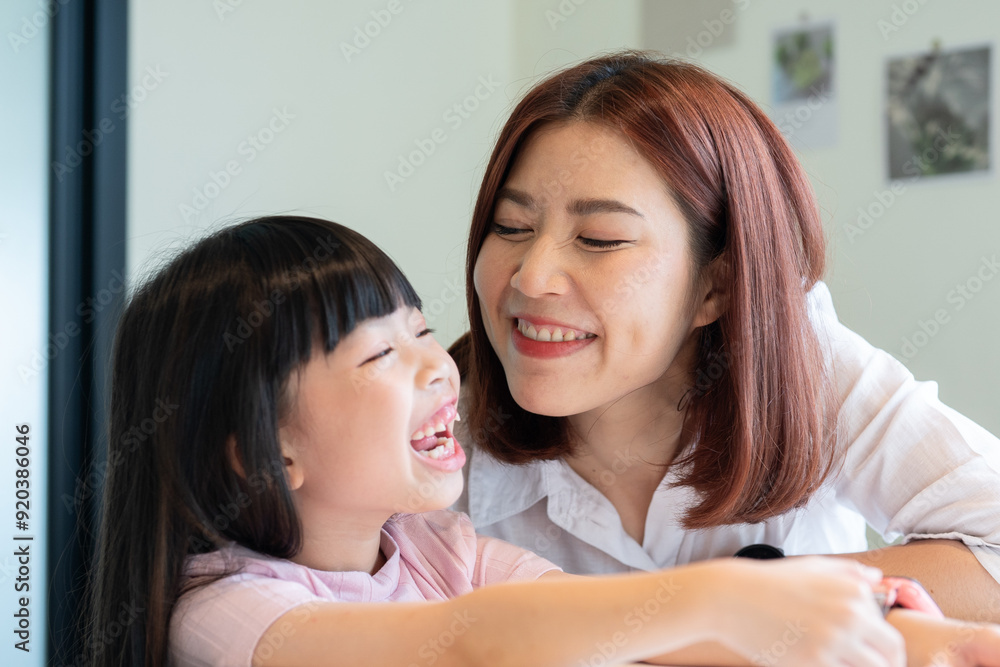 A woman and a little girl are smiling at each other A woman and a little girl are smiling at each other