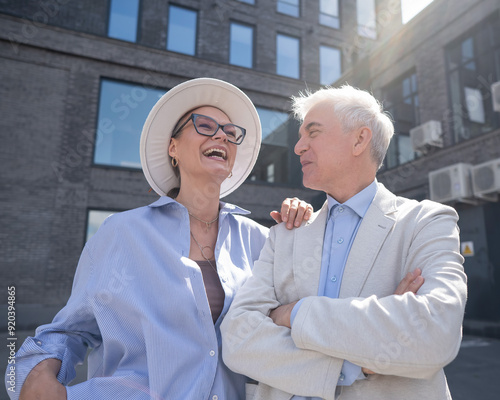 An elderly couple in love walks through the city. Portrait of a stylish gray-haired man and woman.  photo