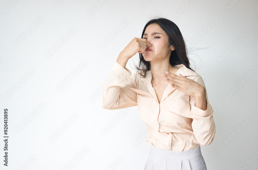 Young Adult Asian Woman covering her nose to prevent bad stinking smell, stinking odor and disgusting expression or reaction Young Adult Asian Woman covering her nose to prevent bad stinking smell, stinking odor and disgusting expression or reaction