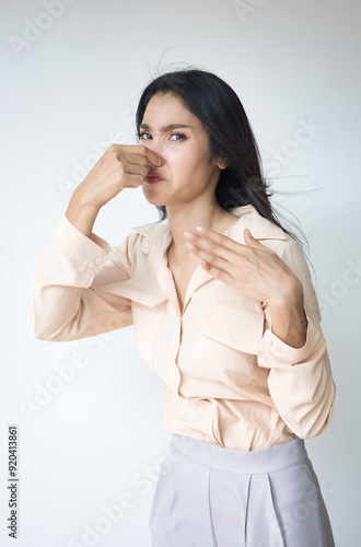 Young Adult Asian Woman covering her nose to prevent bad stinking smell, stinking odor and disgusting expression or reaction