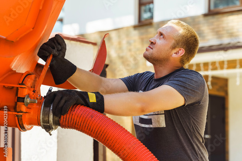 workman connects a suction hose to a sewage tanker truck. Septic tank maintenance. Sewer pumping machine. Septic truck. Pumping wastewater from a septic tank. Septic tank maintenance photo