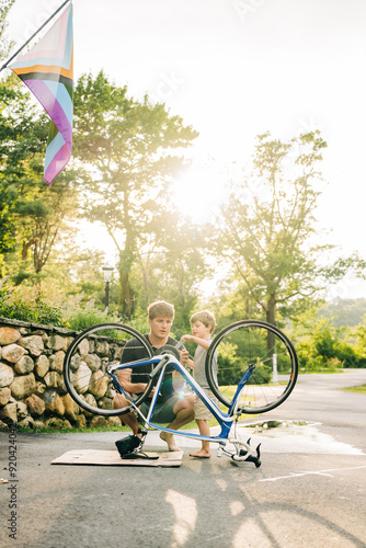 Wallpaper Mural Man and young boy repairing a bicycle in a driveway during sunset Torontodigital.ca