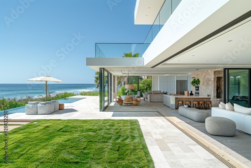 Serene beachside home backyard with light white walls, modern farmhouse style, lush grass, ocean views, outdoor kitchen, and pool in daylight.