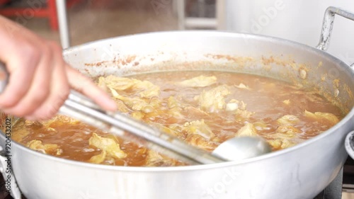 Stirring the pork soup with a large spoon, street food in Ecuador