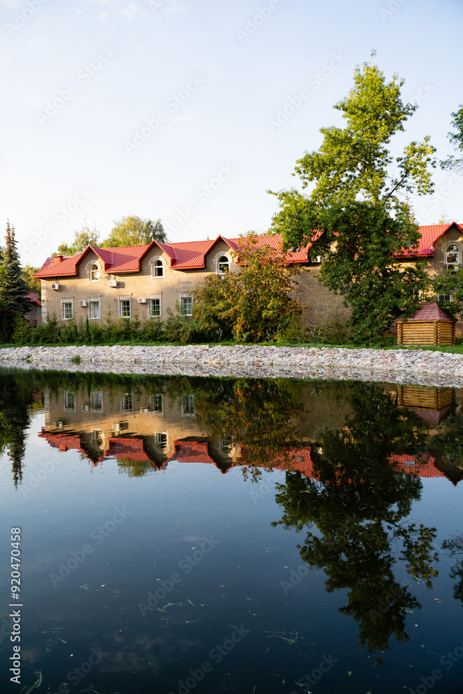 Fototapeta premium A beautiful building featuring striking red roofs is reflected in a serene body of water, creating a picturesque scene that captures the essence of nature and tranquility