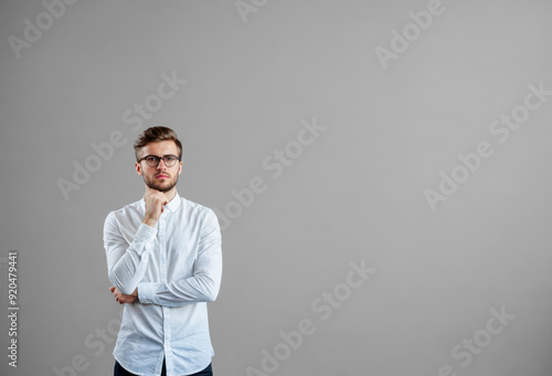 serious, thoughtful young man in process of decision-making or reflection. grey wall background. copy space