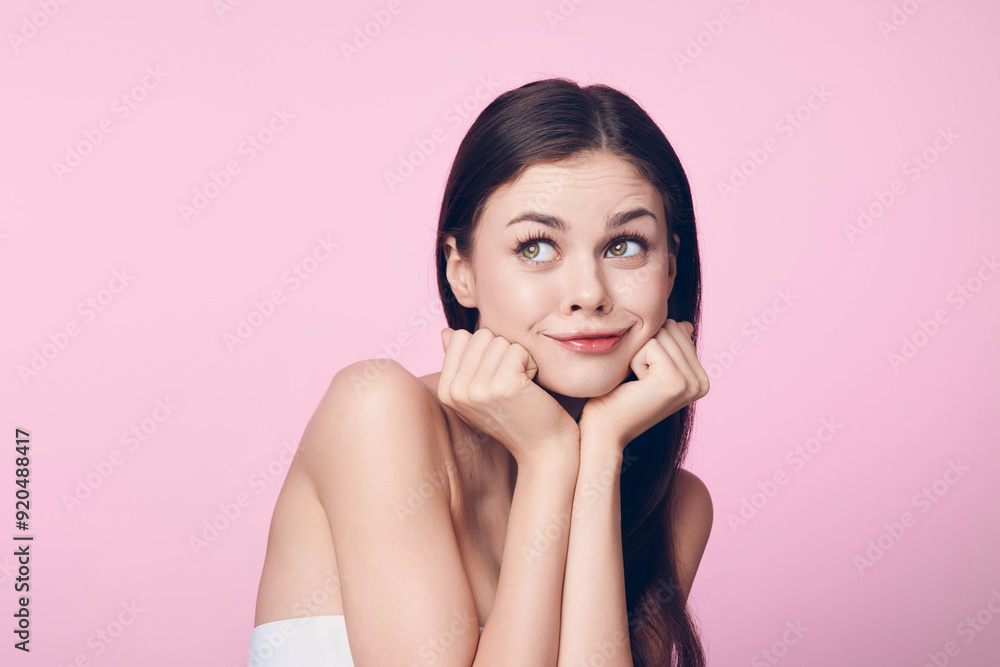 Beautiful young woman posing with her hands on her chin on a pink background Beautiful young woman posing with her hands on her chin on a pink background
