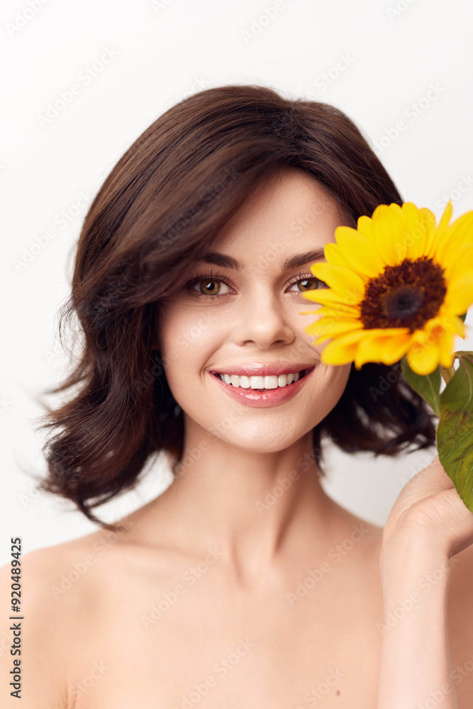 Smiling woman holding sunflower in front of her face Smiling woman holding sunflower in front of her face