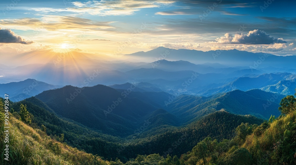 Obraz premium A breathtaking panorama of layered mountains bathed in golden sunlight, casting long shadows across the lush greenery.