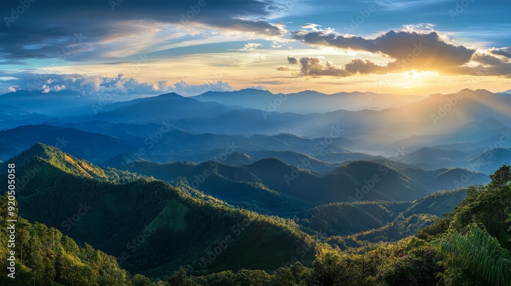 A panoramic view of a mountain range with a golden sunset breaking through the clouds. The mountains are covered in lush green forests. A panoramic view of a mountain range with a golden sunset breaking through the clouds. The mountains are covered in lush green forests.