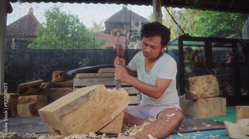 The magic of Balinese wood carving! A master artisan shape exquisite masks with a mallet and carving knife, revealing the beauty of this ancient craft. Ubud, Bali, Indonesia photo