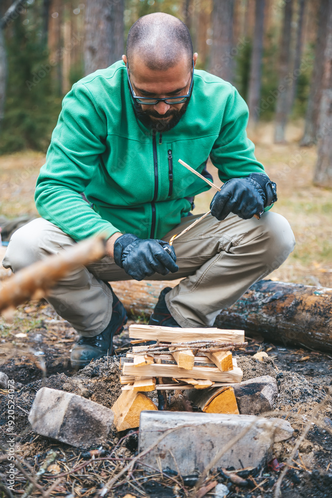 A forest ranger is arranging kindling to ignite a campfire A forest ranger is arranging kindling to ignite a campfire