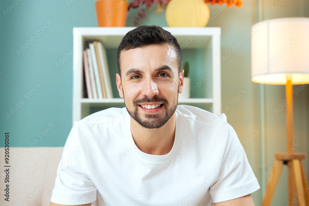 Young Caucasian man sitting on the sofa at home throwing his body forward, smiling and looking at the camera. Young Caucasian man sitting on the sofa at home throwing his body forward, smiling and looking at the camera.