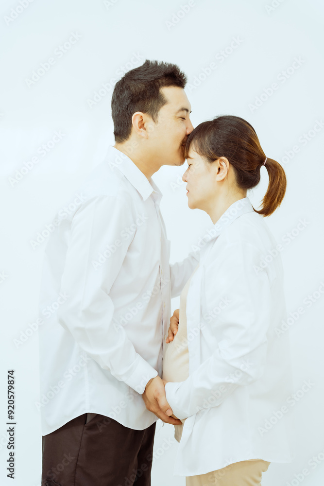 A middle-aged Asian couple, with the woman being pregnant, shares a loving embrace, smiling with happiness and anticipation for their soon-to-arrive baby, symbolizing family togetherness and joy. A middle-aged Asian couple, with the woman being pregnant, shares a loving embrace, smiling with happiness and anticipation for their soon-to-arrive baby, symbolizing family togetherness and joy.
