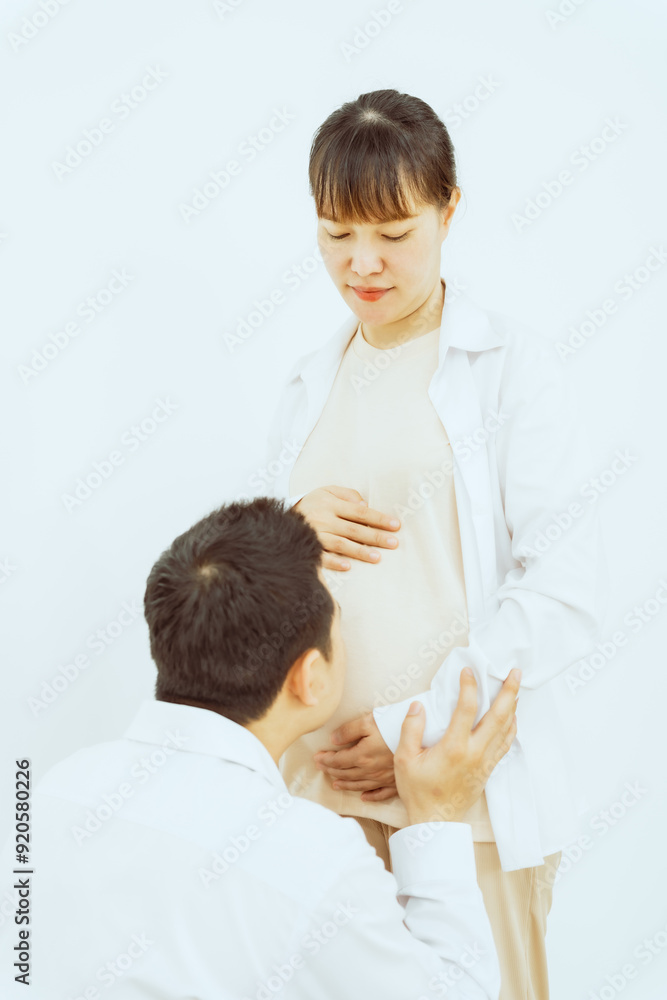 A middle-aged Asian couple, with the woman being pregnant, shares a loving embrace, smiling with happiness and anticipation for their soon-to-arrive baby, symbolizing family togetherness and joy. A middle-aged Asian couple, with the woman being pregnant, shares a loving embrace, smiling with happiness and anticipation for their soon-to-arrive baby, symbolizing family togetherness and joy.