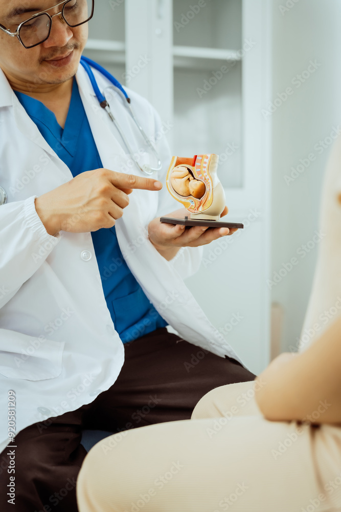 A male Asian pediatrician in a white lab coat sits at his desk, warmly greeting a middle-aged pregnant woman for a prenatal consultation, offering care and support in a clinical setting. A male Asian pediatrician in a white lab coat sits at his desk, warmly greeting a middle-aged pregnant woman for a prenatal consultation, offering care and support in a clinical setting.