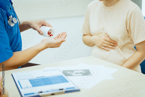 A male Asian pediatrician in a white lab coat conducts a prenatal checkup for a middle-aged pregnant woman, focusing on maternal and fetal health, offering expert care and guidance. photo