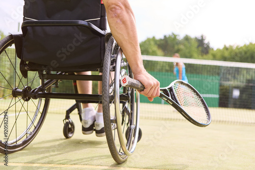 Athlete in wheelchair playing tennis on outdoor court, showcasing determination and skill © Robert Kneschke