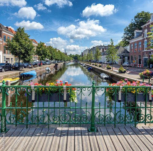 A tranquil canal in The Hague is framed by green railings decorated with vibrant flowers.