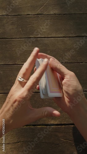 A close-up of hands skillfully shuffling a deck of cards on a rustic wooden surface. The hands move swiftly, displaying precise control and dexterity, suggesting either a card game or a magic trick in