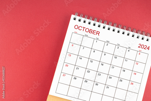 October 2024 desk calendar on red background.