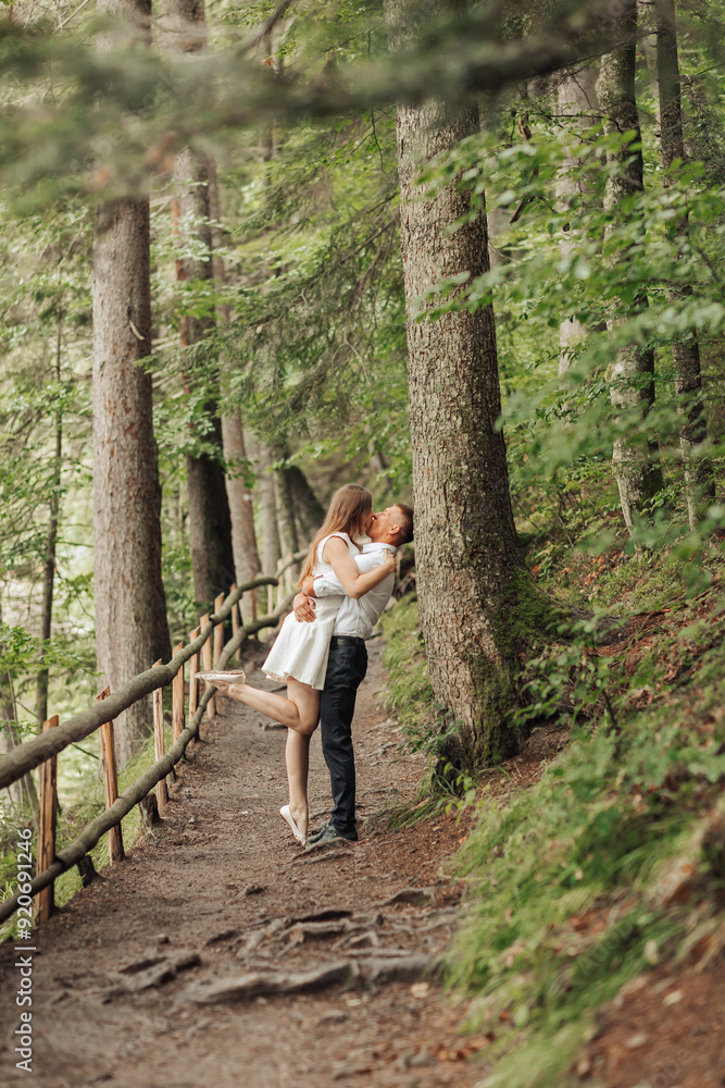 Obraz premium A couple is hugging in a forest, with the man standing behind the woman