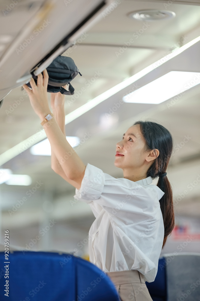 A woman is reaching for a bag on a plane A woman is reaching for a bag on a plane