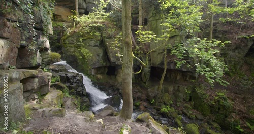 Wide tilting down shot of the Lumsdale waterfalls with rocks and trees in foreground at Lumsdale, Matlock photo