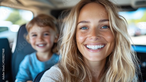 A joyful mother and her beaming son share a happy moment in the car, captured perfectly in this lively selfie. Their genuine smiles reflect the warmth of their bond.